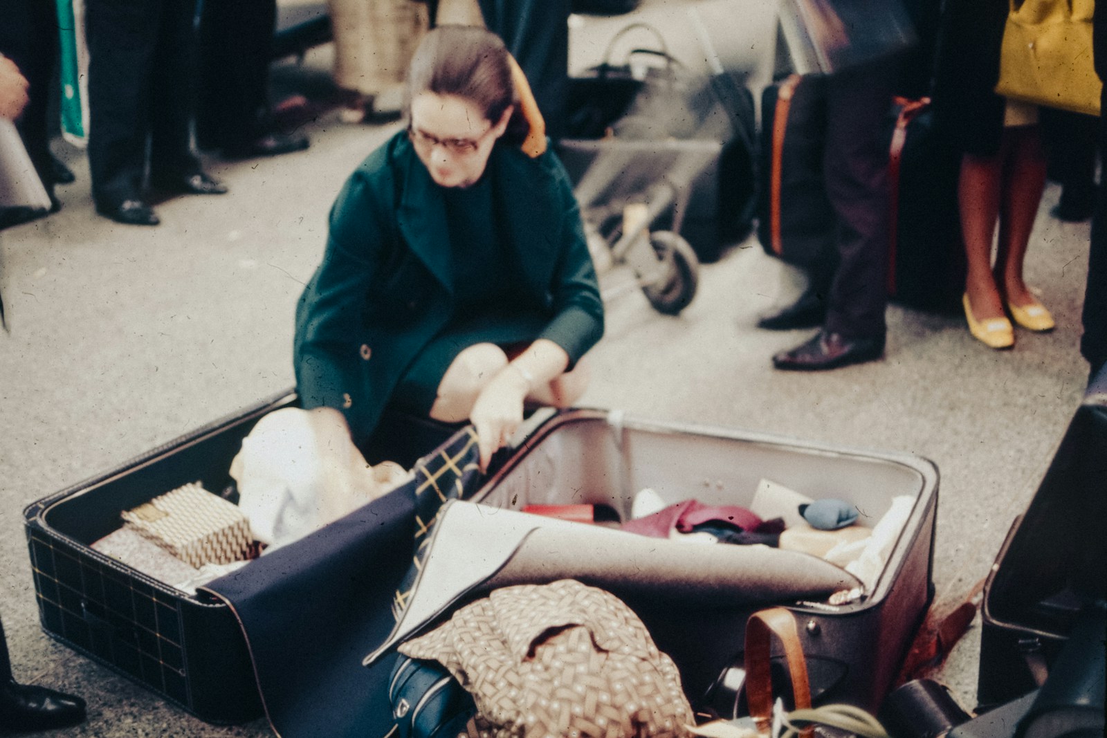 A woman sitting in an open suitcase on the ground