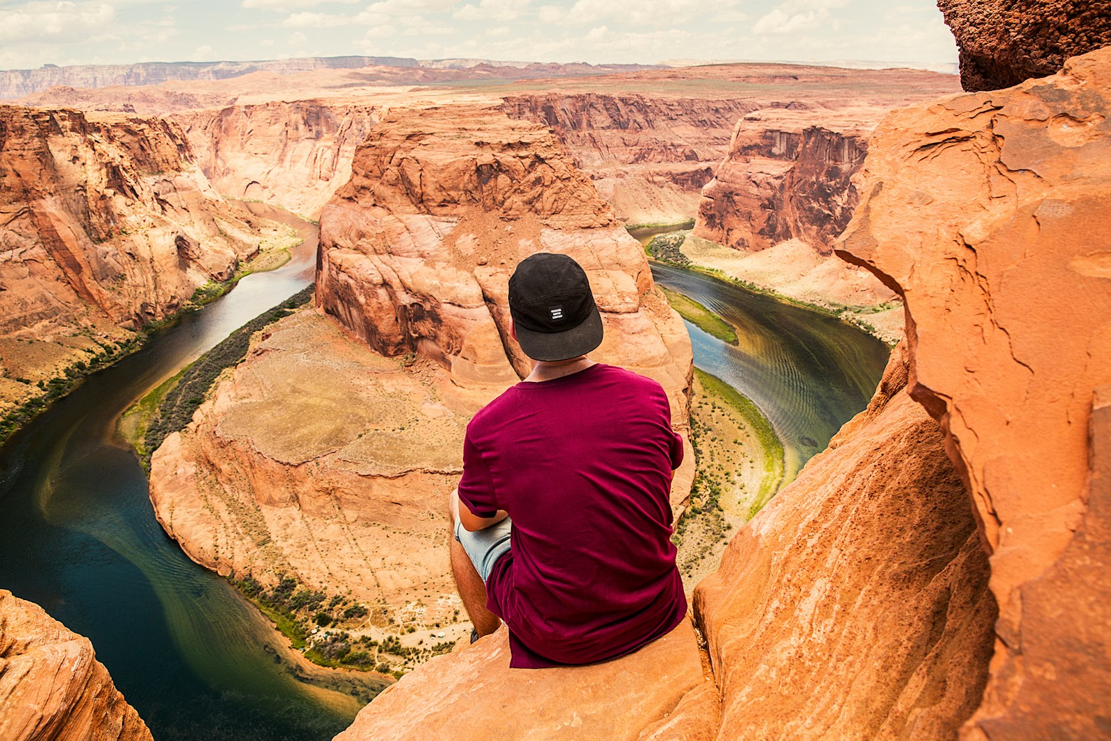 man sitting on brown mountain located at Grand Canyon during daytime