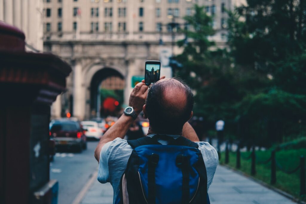 man taking a photo of white high-rise building at daytime